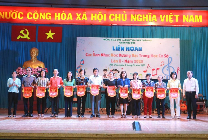 Thầy Dương Hoàng Tuấn (Trưởng phòng Giáo dục và Đào tạo) và chị Lê Thị Hiếu (Phó giám đốc Nhà thiếu nhi) tặng cờ lưu niệm cho đại diện Ban giám hiệu và giáo viên phụ trách của các trường trung học cơ sở. Ảnh: Cẩm Vân.