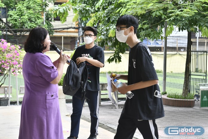 Cô Cao Thanh Nga - Phó Điểm trưởng Điểm thi Trường Trung học phổ thông Phan Huy Chú – Đống Đa hướng dẫn thí sinh di chuyển đến khu vực để đồ dùng không cần thiết. (Ảnh: Ngọc Mai).