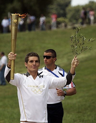 Spyros Gianniotis cầm cây đuốc và cành ô liu trên tay...