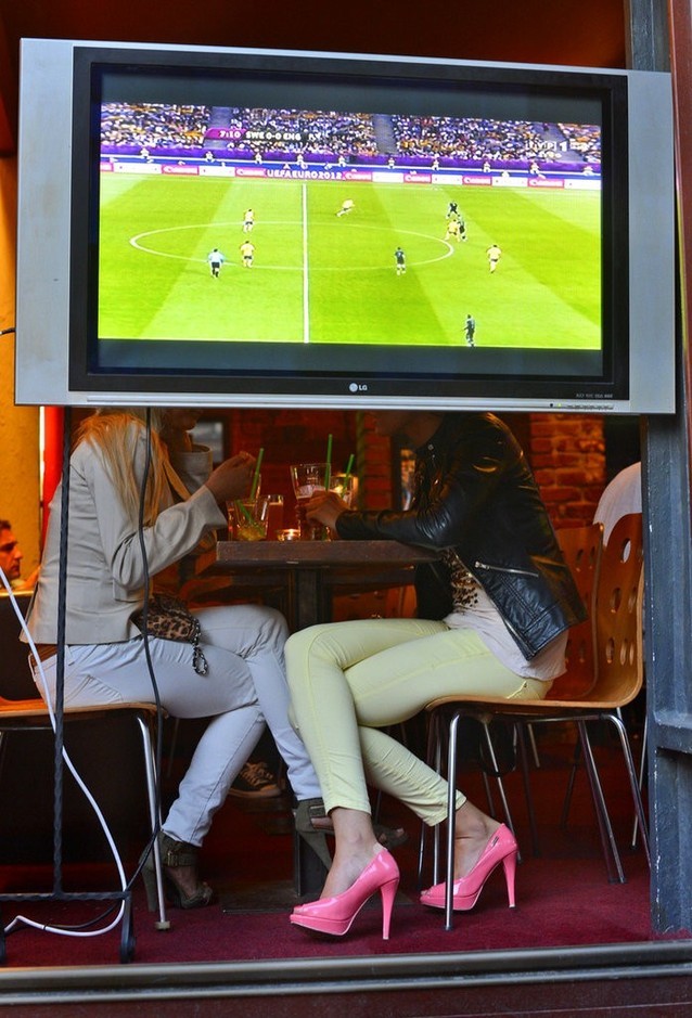 Hai cô gái ngôi uống nước sau màn hình TV trong một quán bar ở Wrocław, Ba Lan.