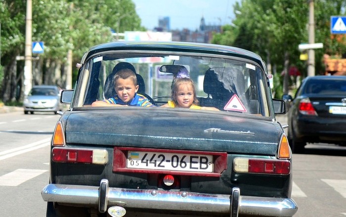 Trẻ em nhìn qua cửa kính ô tô đang đi trên đường phố Donetsk, Ukraina.