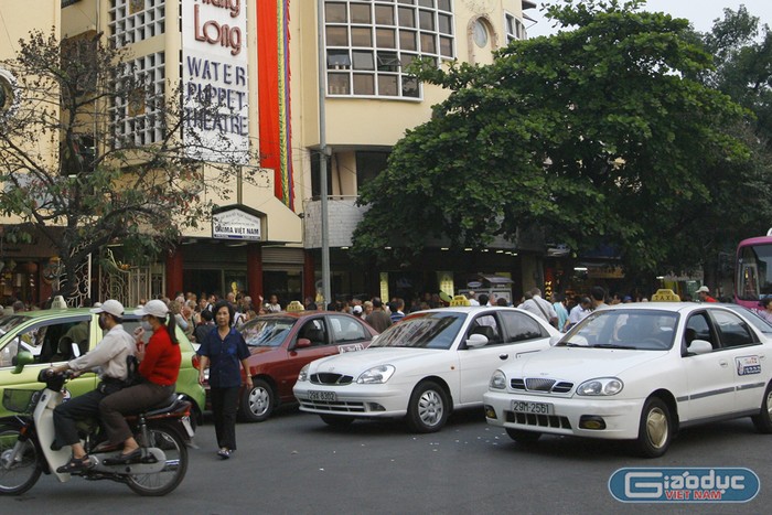 Xe taxi đỗ hàng 3 ngay dưới lòng đường để đón khách gây cản trở giao thông. Ảnh: Tùng Dương.