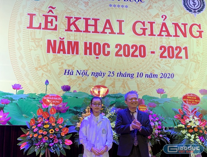 Giáo sư, tiến sĩ Lê Ngọc Thành - Giám đốc Bệnh viện E, Chủ nhiệm Khoa Y Dược đã trao tặng áo Blue trắng cho sinh viên, thủ khoa đầu vào Hoàng Thị Huyền. Ảnh: Tùng Dương.