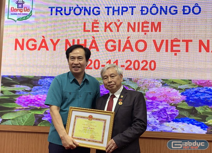 Ông Nguyễn Anh Tuấn (bên trái ảnh) Phó Bí thư thường trực quận Ủy Tây Hồ đang trao giấy khen và huy hiệu 40 năm tuổi Đảng cho Tiến sĩ Võ Thế Quân - Hiệu trưởng Trường Trung học phổ thông Đông Đô. Ảnh: Tùng Dương.