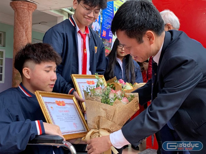 Thầy Đàm Tiến Nam - Hiệu trưởng Trường Trung học phổ thông Nguyễn Bỉnh Khiêm tặng hoa cho em Nguyễn Quang Mạnh. Ảnh: Tùng Dương.