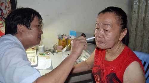 Bác sĩ Hoàng Văn Minh, trưởng phòng khám da liễu Bệnh viện Đại học Y dược, khám da mặt chị Phượng - Ảnh: VIỄN SỰ