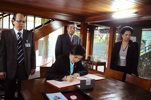 Bà Yingluck ghi cảm xúc trên cuốn sổ lưu niệm sau khi chứng kiến những kỷ vật và đồ dùng làm việc một thời của Hồ Chủ tịch.