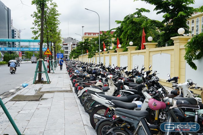 Khu vực ngoài điểm thi, lực lượng thanh niên tình nguyện và cảnh sát giao thông hướng dẫn phụ huynh, học sinh đỗ xe đúng nơi quy định để đảm bảo an ninh trật tự (Ảnh: Phạm Linh)