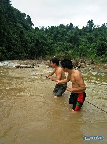 Học sinh qua suối không có cầu, chỉ có những chiếc bè mảng. Sau mưa bão, những chiếc bè mảng bị trôi tuột đi mất, đang được các thầy cô giáo kéo lại. ảnh: Xuân Quang.