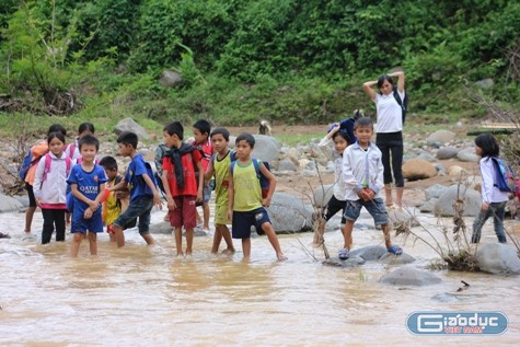 Mỗi khi tan trường, hàng chục học sinh tập hợp lại thành từng nhóm, lội lõm bõm ven bờ đến vị trí đặt cầu tạm để qua suối. Ảnh: Xuân Quang.