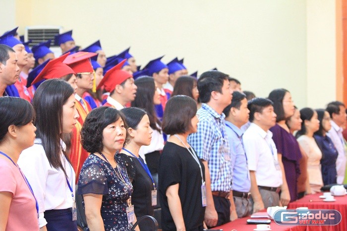 Lãnh đạo nhà trường cùng các tân thạc sĩ, tiến sĩ làm lễ chào cờ. Ảnh của Xuân Quang.