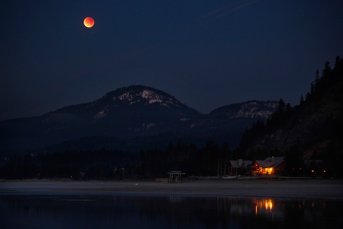 Mặt trăng có màu đỏ bầm do hiện tượng nguyệt thực mọc trên hồ Pend Oreille, sau rặng núi Selkirk, gần Sandpoint, Idaho, 10/12/2011.