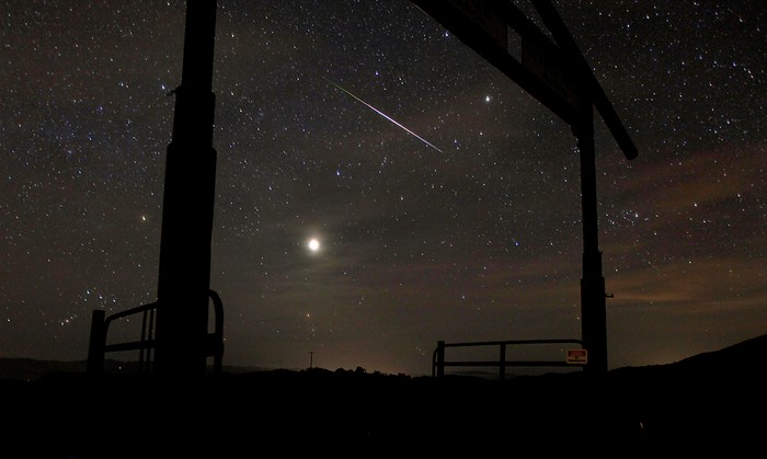 Một ngôi sao băng xẹt qua bầu trời đêm khi hiện tượng nguyệt thực đang xảy ra trên cổng vào trang trại chăn nuôi Hawkeye, gần Geyserville, California, 10/12/2011.