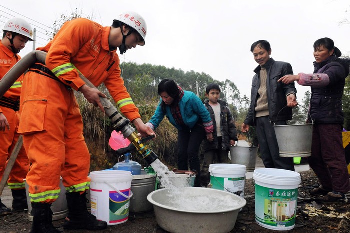 13. Nhân viên cứu hỏa phun nước vào thùng của những người dân làng Xiuliu, ngôi làng nằm dọc theo sông Liujiang, Liễu Châu, thuộc khu tự trị Quảng Tây, Trung Quốc. Sự cố trong những đợt thăm dò địa chất đã khiến cho ô nhiễm trên sông ngày ngày càng tăng.