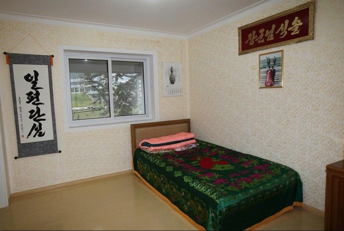 Căn phòng ngủ nhỏ nhắn của gia đình nhưng được bố trí đẹp mắt với tấm ảnh chủ nhà chụp bên chân tượng đìa hai nhà lãnh đạo Kim Nhật Thành và Kim Jong-il ở Bình Nhưỡng.
