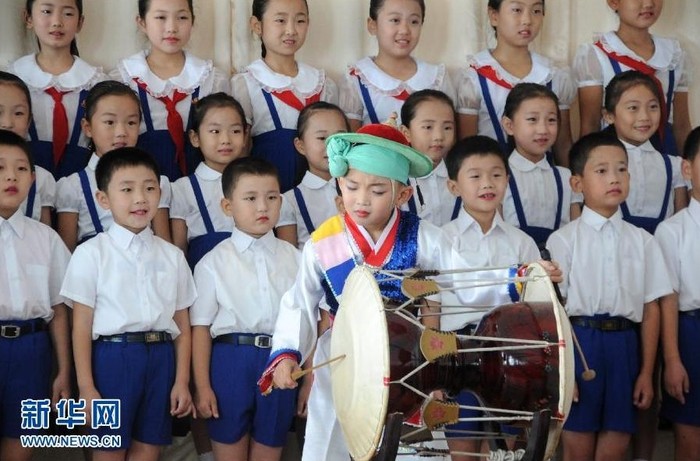 Các học sinh tiểu học trong một buổi diễn văn nghệ. Một cậu bé đứng trên đang biểu diễn nghệ thuật trống truyền thống.