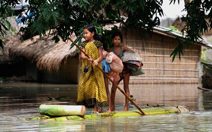 Những đứa trẻ đi bằng bè chuối ở làng Burhabrhi, phía đông của Gauhati, bang Assam, Ấn Độ