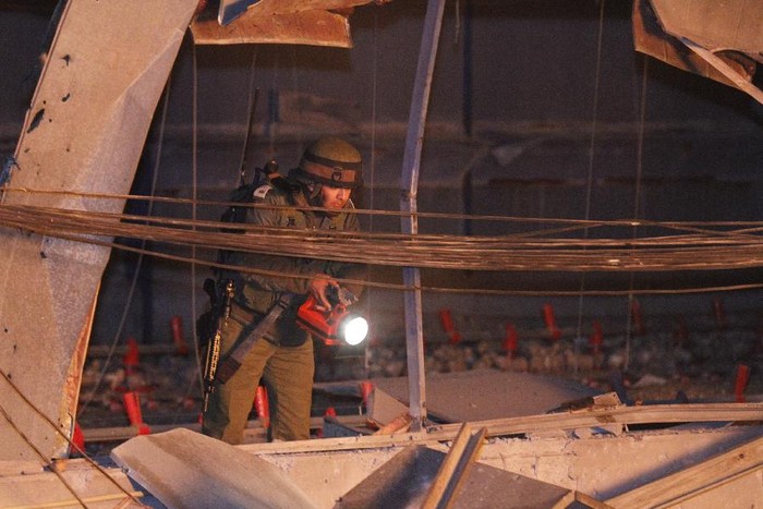 Một binh sĩ Israel đang kiểm tra tòa nhà bị hư hỏng do trúng tên lửa từ Lebanon