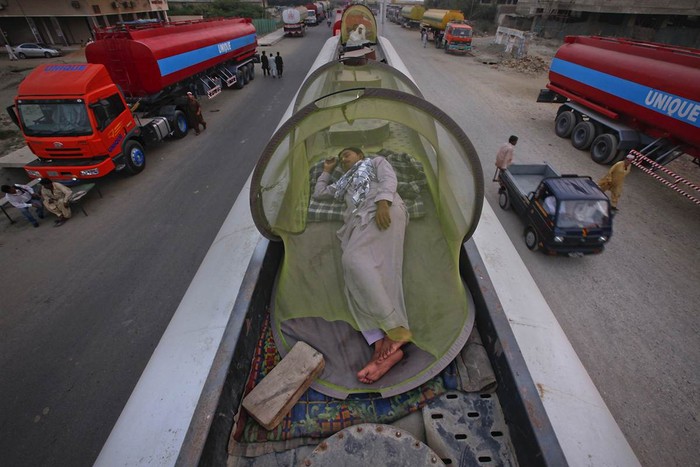 Một người chở nhiên liệu cho lực lượng NATO tại Afghanistan đang ngủ trên xe tải của họ ở Karachi, Pakistan hôm 26/11. Hoạt động cung cấp nhiên liệu và vũ khí cho lực lượng NATO tại Afghanistan đã bị gián đoạn sau khi Pakistan tuyên bố đóng cửa biên giới vĩnh viễn đối với NATO sau sự kiện không kích hai tiền đồn quân sự của nước này tại khu vực biên giới làm 24 binh sĩ thiệt mạng.