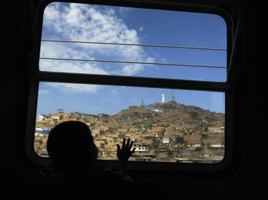 Một cậu bé mải ngắm cảnh qua ô cửa sổ của chuyến tàu điện miễn phí tại Lima, Peru ngày 5/1