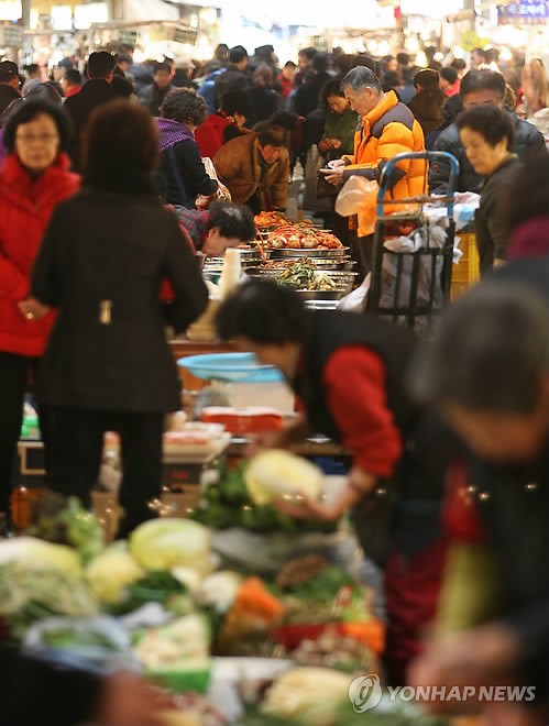 Những người vô gia cư xếp hàng chờ được phát miễn phí món "ddeoggug", một món ăn truyền thống trong dịp Tết âm lịch của người Hàn Quốc. Một góc khu chợ đông người đi sắm Tết ở Seoul