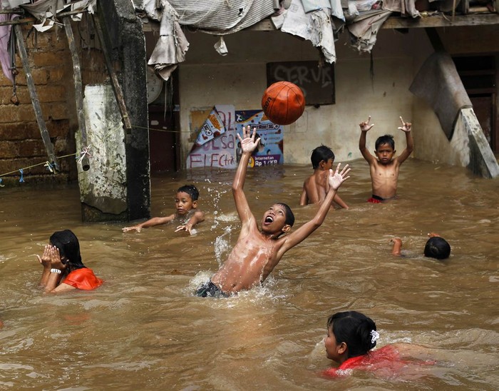 Trẻ em chơi đùa với quả bóng trong trận lụt gần nhà của chúng ở Jakarta ngày 23/2.