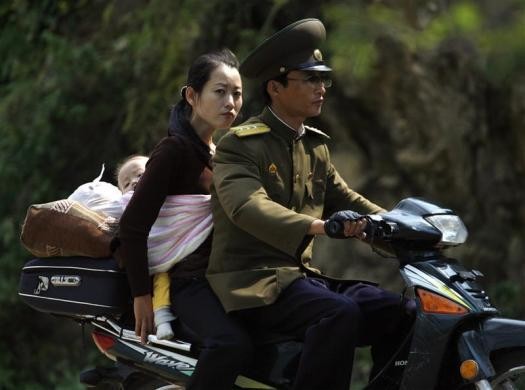Một bà mẹ địu con ngồi sau chiếc xe máy do một chiến sĩ Triều Tiên điều khiển tại Yalu ngày 12/9/2008.