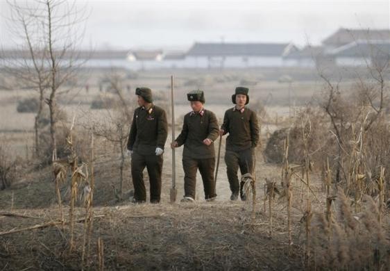 Các chiến sĩ Triều Tiên đi bộ trên cánh đồng ngô đã thu hoạch tại thị trấn biên giới của Sinujiu ngày 22/11/2009.