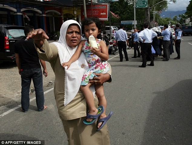 Một phụ nữ bế con nhỏ cố gắng bắt taxi để di chuyển tới khu vực cao hơn
