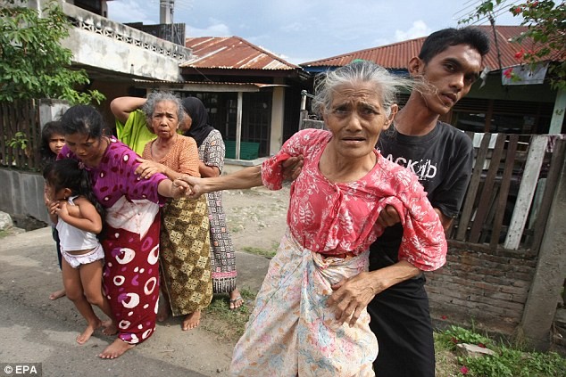 Một phụ nữ cao tuổi được người thân giúp đỡ rời thành phố