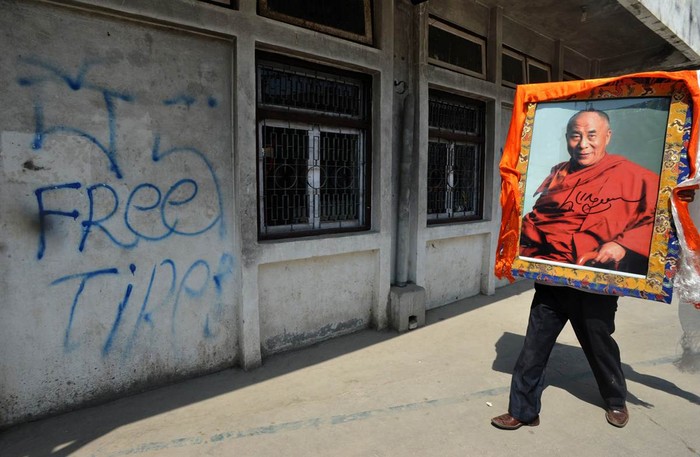 Một người Tây Tạng lưu vong mang bức chân dung Đạt Lai Lạt Ma tại Boudha, Kathmandu, Nepal ngày 25/4.