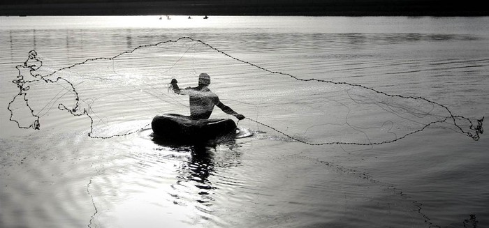 Một ngư dân ngồi trên chiếc vòng cao su quăng lưới đánh cá tại sông Sabarmati, Ahmedabad, miền tây Ấn Độ ngày 22/5.