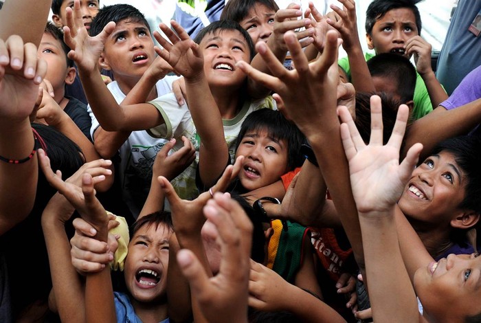 Trẻ em chen lấn, nhảy lên túm lấy đồ chơi và các đồ vật khác được treo lơ lửng trên không trong lễ hội đường phố hàng năm Feast Day ở Manila, Philippines ngày 20/5.