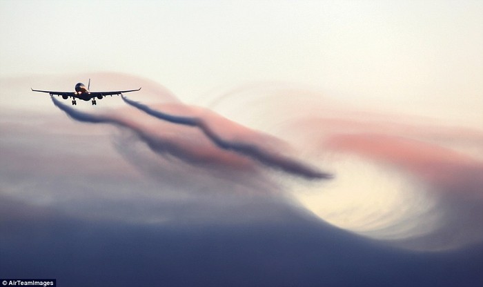 Máy bay đi qua đỉnh một đám mây đỏ tạo ra hiệu ứng sóng ngoạn mục.