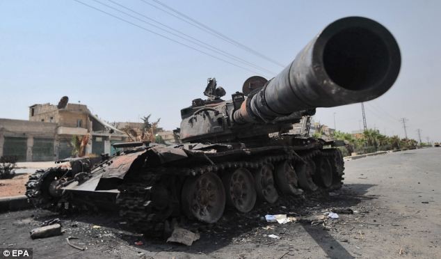 Một chiếc xe tăng của quân chính phủ bị phá hủy và bỏ lại trên đường phố gần Aleppo.