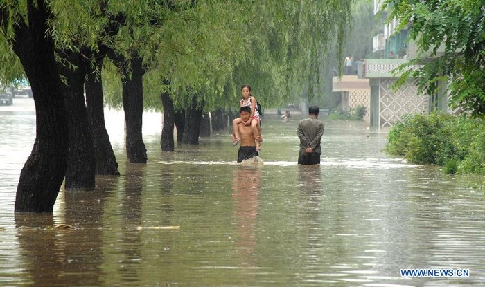 Người dân đi trên phố Anju, nơi nước ngập lên tới nửa người.