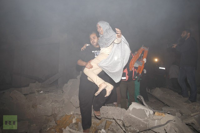 Người đàn ông Palestine giúp đỡ một phụ nữ ra khỏi đống đổ nát do trúng tên lửa của Israel.