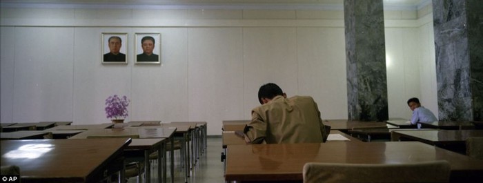 Nam thanh niên đang nghiên cứu tại Grand People's Study House. Trên bức tường trước mặt họ là chân dung của 2 cố nhà lãnh đạo Kim Nhật Thành và Kim Jong-il.