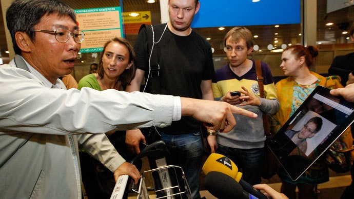 Một nhà báo chỉ cho hành khách đến từ Hồng Kông xem hình của Snowden tại sân bay quốc tế Sheremetyevo, Moscow hôm 23/6 để tìm hiểu xem anh có mặt trên chuyến bay của họ hay không.
