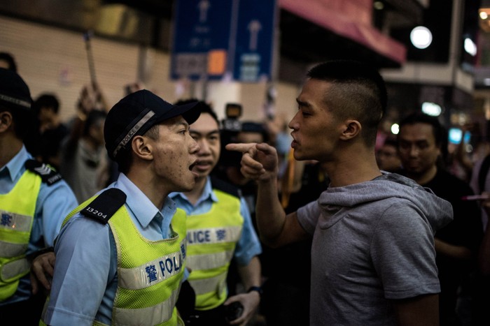 Cảnh sát tranh cãi với một người đàn ông tấn công những người biểu tình phản đối chính phủ.