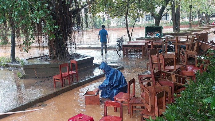 Thầy cô giáo phải mang bàn ghế học sinh ra vệ sinh, chùi rửa trong mưa. Ảnh: AN