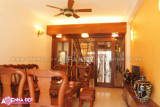 Phòng khách được bố trí với một bộ bàn ghế gỗ lớn ở trung tâm, tạo nên sự sang trọng cho ngôi nhà.