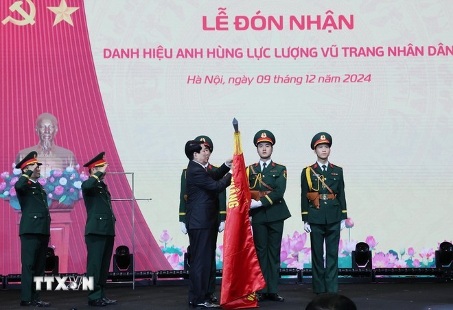 Chủ tịch nước Lương Cường gắn huy hiệu Anh hùng Lực lượng vũ trang nhân dân lên lá cờ truyền thống Viện Hàng không Vũ trụ Viettel. (Ảnh: Lâm Khánh/TTXVN)