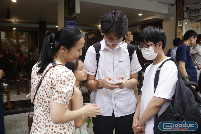 Em Bùi Nam Khánh đang cầm điện thoại để kiểm tra kết quả xem câu hỏi khó trong bài thi tiếng Anh em làm đúng hay chưa. (Ảnh: Ngọc Mai) GDVN (558).JPG