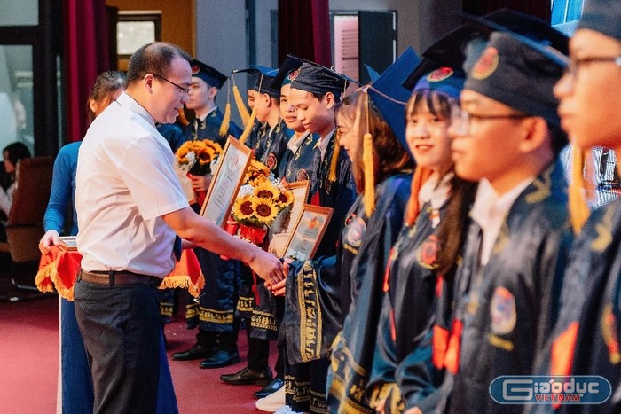 Thầy Nguyễn Minh Đức – Phó Hiệu trưởng Nhà trường tặng hoa chúc mừng 33 sinh viên tốt nghiệp thủ khoa các chuyên ngành (Ảnh: Lã Tiến)